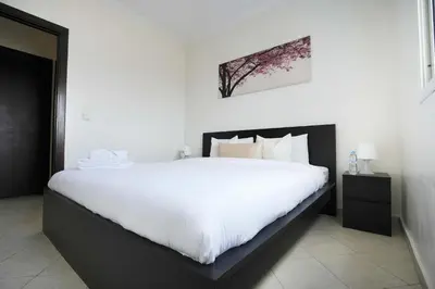 a bedroom with a large bed with white sheets at Cozy Apartment in the Heart of Bouznika in Bouznika