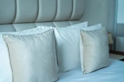 a group of four white pillows on a bed at Appartement Élégant au Cœur de Central Park in Mohammedia