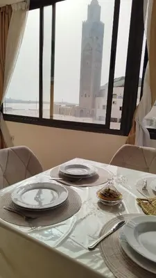 a table with plates and utensils on it with a clock tower at Spacious Apartment with Panoramic Ocean Views in Casablanca