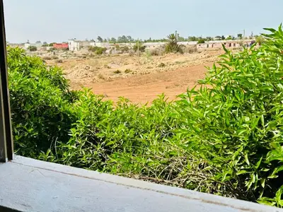 a view of a field from a window with bushes at Belle maison avec piscine à 7 min de la plage en voiture in Dar Bouazza