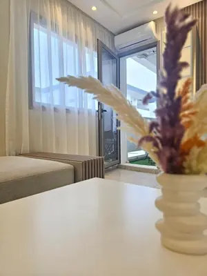 a living room with a table and a vase with a flower at Appartement El Mansouria Séjour Luxueux Plage & vue Piscine in Mansouria