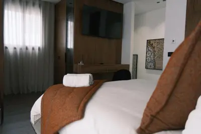 a hotel room with a bed and a television at Luxury Warm-Wood Duplex - Rooftop Sky Pool Access in Casablanca