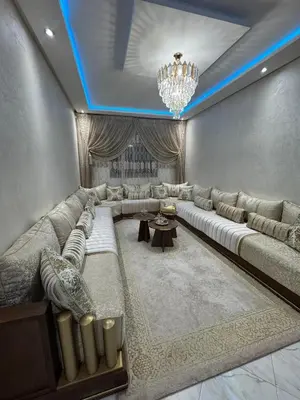 a living room with a large couch and a chandelier at Appartement abwab tamaris in Dar Mouddene