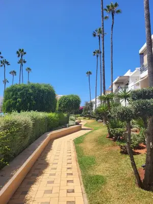 a walkway near the beach with palm trees and condos at Superbe appartement de 3 chambres avec piscines in Tamaris