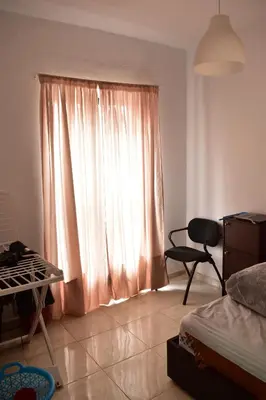 a bedroom with a bed and a window with a chair at Havre de paix appartement in Mohammedia