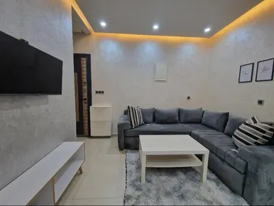 a living room with a blue couch and a tv at Appartement bien meublé in Rabat