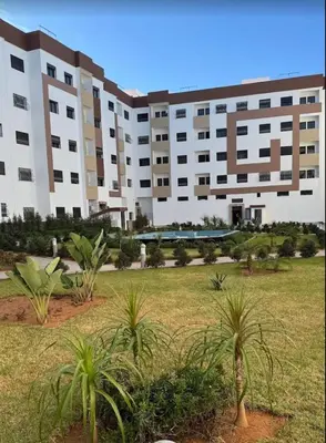 an apartment building with palm trees in front of it at appartement meublé temara in Temara