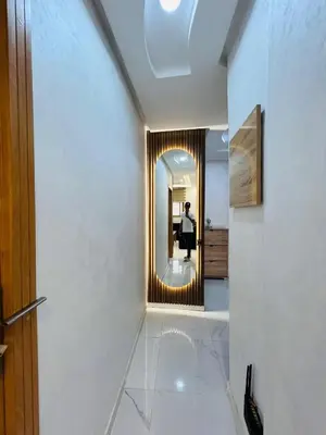 a hallway with a mirror and a woman standing in the doorway at Modern Apartment Bouznika in Bouznika