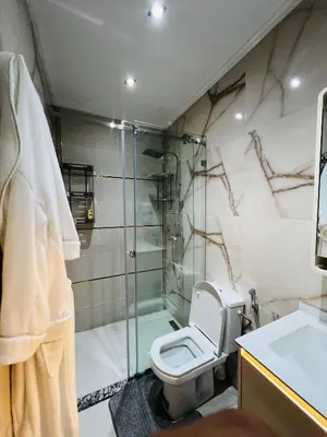 a bathroom with a toilet and a glass shower at Modern Apartment Bouznika in Bouznika