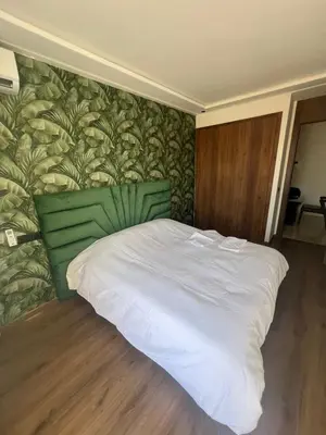 a white bed in a bedroom with a green wall at Adam résidence in Casablanca