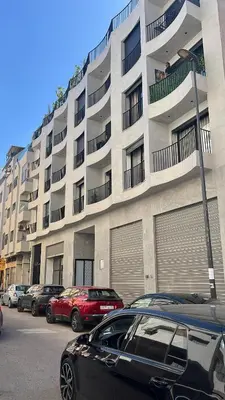 a parking lot with cars parked in front of a building at Cozy Studio Steps from Med V Stadium in Casablanca