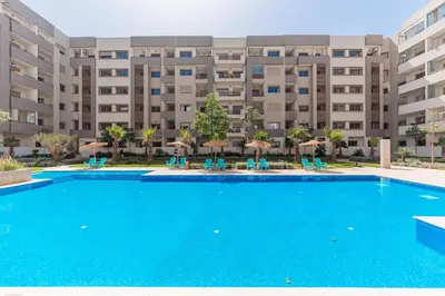 a swimming pool in front of a large apartment building at L'Horizon - 1 BR - Pool & Terrace in Nouaseur