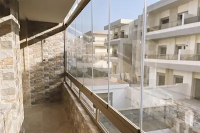 a balcony of a building with glass windows at Modern apartment with pool parking in O Ben Slimane
