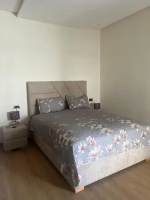a bedroom with a bed with a blue blanket and pillows at Appartement Èlégant Vue piscine in Casablanca