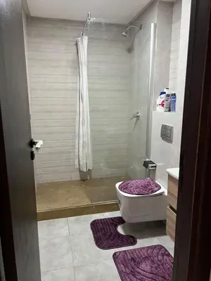 a bathroom with a shower and a toilet with purple rugs at Appartement Èlégant Vue piscine in Casablanca