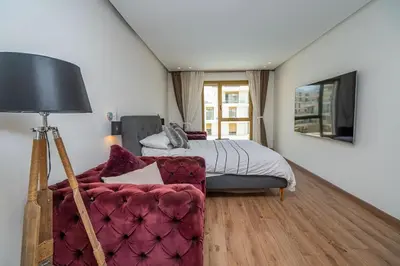 a bedroom with a bed and a couch and a television at escapade de luxe face a la mer in Rabat