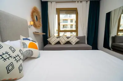 a bedroom with a white bed with pillows and a window at escapade de luxe face a la mer in Rabat