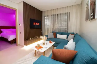 a living room with a blue couch and a bed at Studio élégant et neuf près de la gare tgv in Casablanca