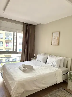 a white bed with a towel on top of it at N22 Élégance et Confort à La Corniche Rabat - Appartement de Luxe Essabah in Rabat