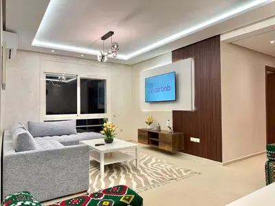 a living room with a couch and a tv at N22 Élégance et Confort à La Corniche Rabat - Appartement de Luxe Essabah in Rabat