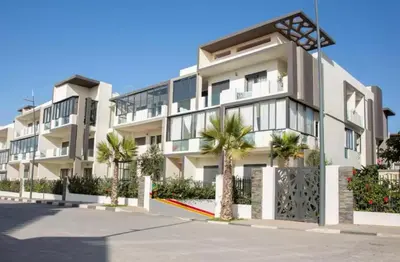 a large white building with palm trees in front of it at Appartement tamaris les crêtes in Casablanca