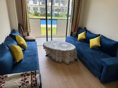 a living room with a blue couch and a table at Appartement tamaris les crêtes in Casablanca
