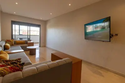 a living room with a couch and a flat screen tv at Family apartment Terrace Pool Wi-Fi in O Ben Slimane