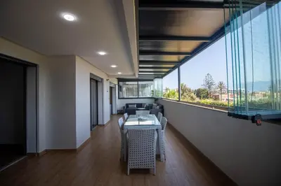 a room with a table and chairs and a large window at Family apartment Terrace Pool Wi-Fi in O Ben Slimane