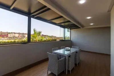a dining room with a table and chairs and a large window at Family apartment Terrace Pool Wi-Fi in O Ben Slimane