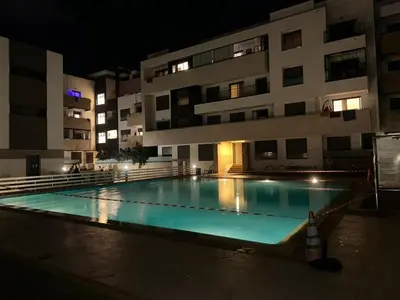 a swimming pool in front of a building at night at Family apartment Terrace Pool Wi-Fi in O Ben Slimane