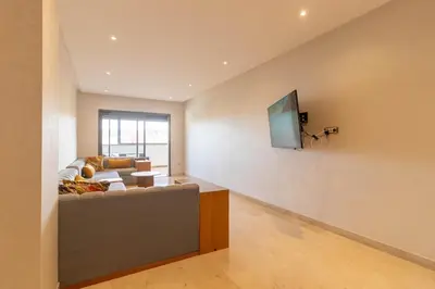 a living room with a couch and a tv on a wall at Family apartment Terrace Pool Wi-Fi in O Ben Slimane