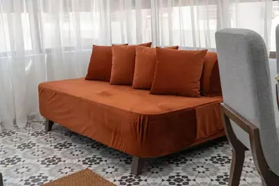 a bed with orange sheets and a chair in a room at Mansouria 1BR Pool View Beach Parking in Mansouria
