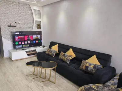 a living room with a black couch and a flat screen tv at Mansbay Beach Dalia in Mohammedia