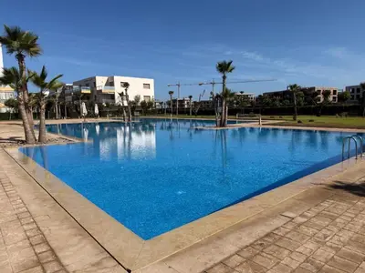 a large blue swimming pool with palm trees and buildings at Blue Beach in Casablanca