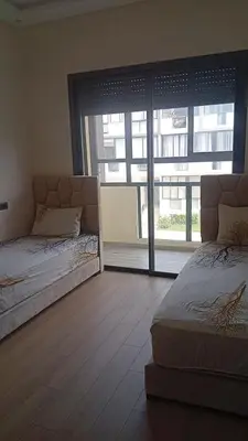 two beds in a room with a large window at Elegance Pool View Apartment in Dar Bouazza