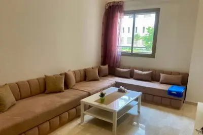 a living room with a couch and a table at Appartement Moderne et Équipé Proche Aéroport CMN in Nouaseur
