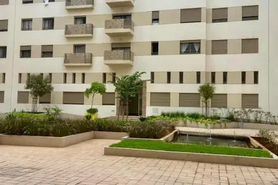 a building with a courtyard with a fountain in front of it at Appartement Moderne et Équipé Proche Aéroport CMN in Nouaseur