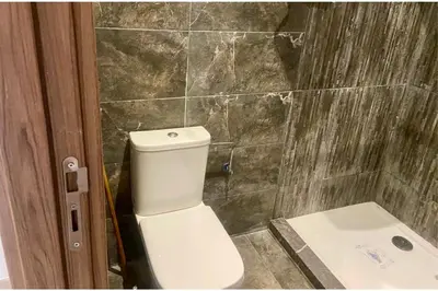 a bathroom with a toilet and a stone wall at Appartement Moderne et Équipé Proche Aéroport CMN in Nouaseur