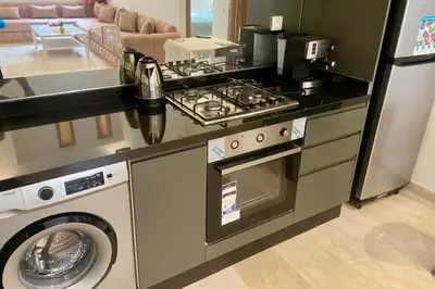 a kitchen with a stove and a washing machine at Appartement Moderne et Équipé Proche Aéroport CMN in Nouaseur