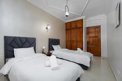 a bedroom with two beds with white sheets at Harhoura Luxury Stay, Steps from the Beach in Temara