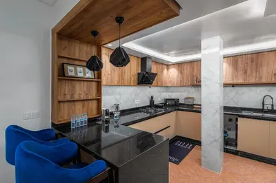 a kitchen with wooden cabinets and blue chairs at Harhoura Luxury Stay, Steps from the Beach in Temara
