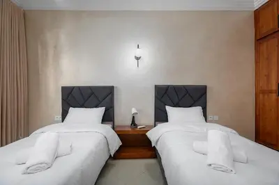 two beds with white sheets in a room at Harhoura Luxury Stay, Steps from the Beach in Temara