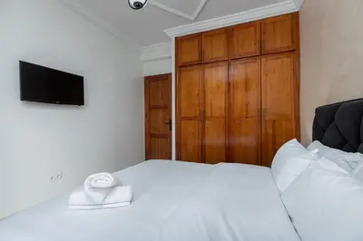 a bedroom with a white bed with a television on it at Harhoura Luxury Stay, Steps from the Beach in Temara