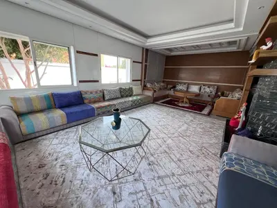 a living room with a couch and a table at Villa piscine in Temara