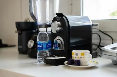 a coffee maker and a cup of water on a counter at Luxury 3 Bedroom Apartment in the Heart of CFC with Swimming pool in Casablanca