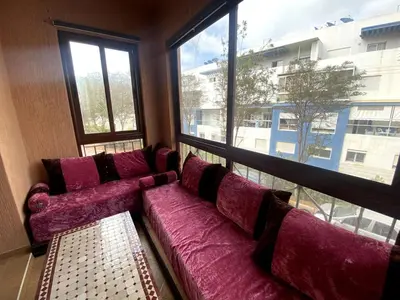 a large purple couch in a room with a large window at Appartement à louer à Mansouria in Mansouria