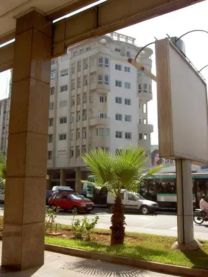 a large white building with a palm tree in front of it at Modern and cozy - Central apartment in Casablanca in Casablanca