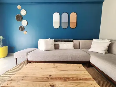 a living room with a couch and a blue wall at The 41 Maarif by IB Signature - Boho Chic 1BR Apt - with Wifi - Self check-in - 24 x7 Security - City View with terrace - Walk to Cafes! City Centre in Casablanca