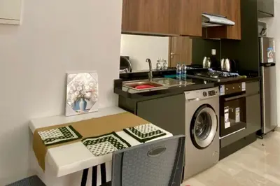 a small kitchen with a table and a washing machine at Appartement Moderne Équipé Proche Aéroport Mohammed V in Nouaseur