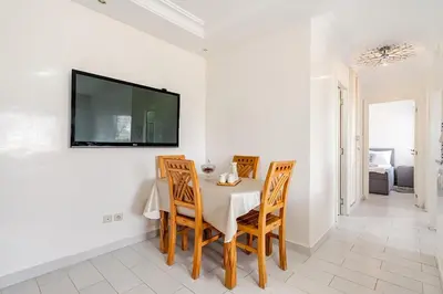 a dining room with a table and chairs and a tv on the wall at Comfort Pool Apartment Heart of Tamaris in Tamaris
